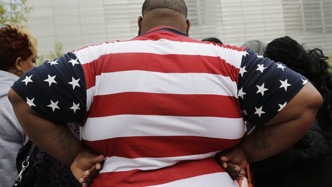 In this May 8, 2014 photo, an overweight man wears a shirt patterned after the American flag during a visit to the World Trade Center, in New York. Rising numbers of American adults have the most dangerous kind of obesity, belly fat, despite evidence that overall obesity rates may have plateaued, government data shows. Abdominal obesity affects 54 percent of U.S. adults, versus 46 percent in 1999-2000, and the average waist size crept up an inch, too, according to the most recent statistics.