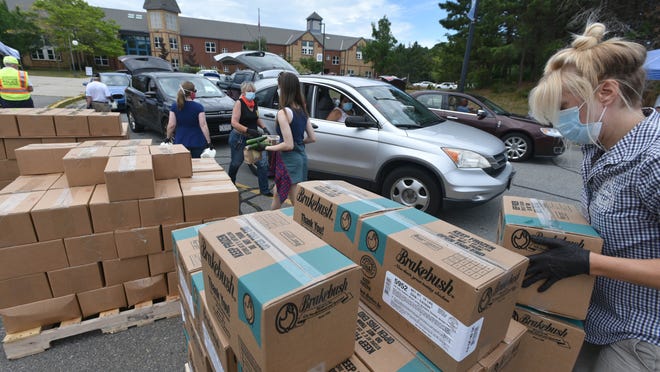 Rebecca Westgate loads up on chicken Wednesday as a long line waits for food at the Oak Ridge School in Sandwich, the site of a  Farmers to Families food giveaway.