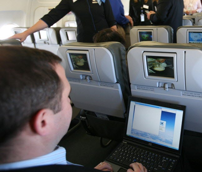 A person demonstrates the capabilities of a laptop during a media preview flight aboard 