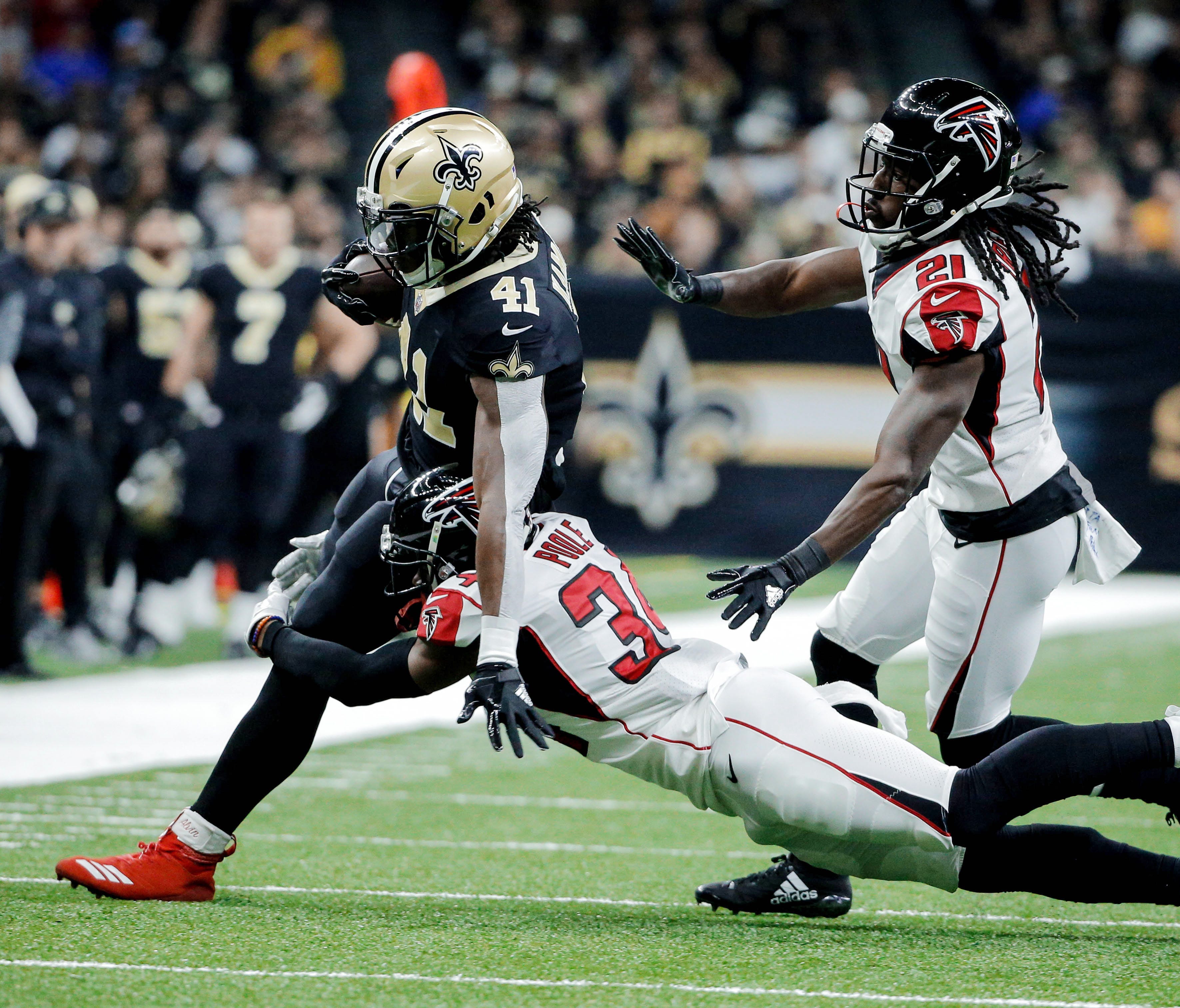 New Orleans Saints running back Alvin Kamara (41) is tackled by Atlanta Falcons cornerback Brian Poole (34) and cornerback Desmond Trufant (21) during the first quarter at the Mercedes-Benz Superdome.