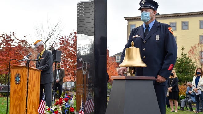 Marblehead firefighter Patrick O'Shea rings the bell during roll call during a Veterans Day ceremony at Memorial Park on Wednesday, Nov. 11, 2020.