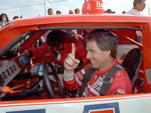 NASCAR driver Darrell Waltrip signals he is number