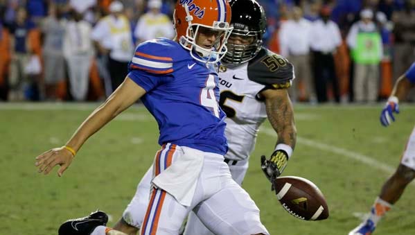 Florida punter Kyle Christy (4) manages to punt the ball after a bad snap as Missouri defensive lineman Shane Ray (56) tries to stop him during the first half of an NCAA college football game in Gainesville, Fla., Saturday, Oct. 18, 2014. (AP Photo/John Raoux)