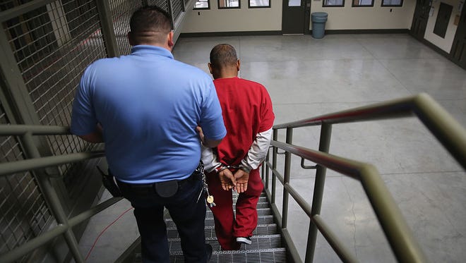FILE - A guard escorts an immigrant detainee at the Adelanto Detention Facility.