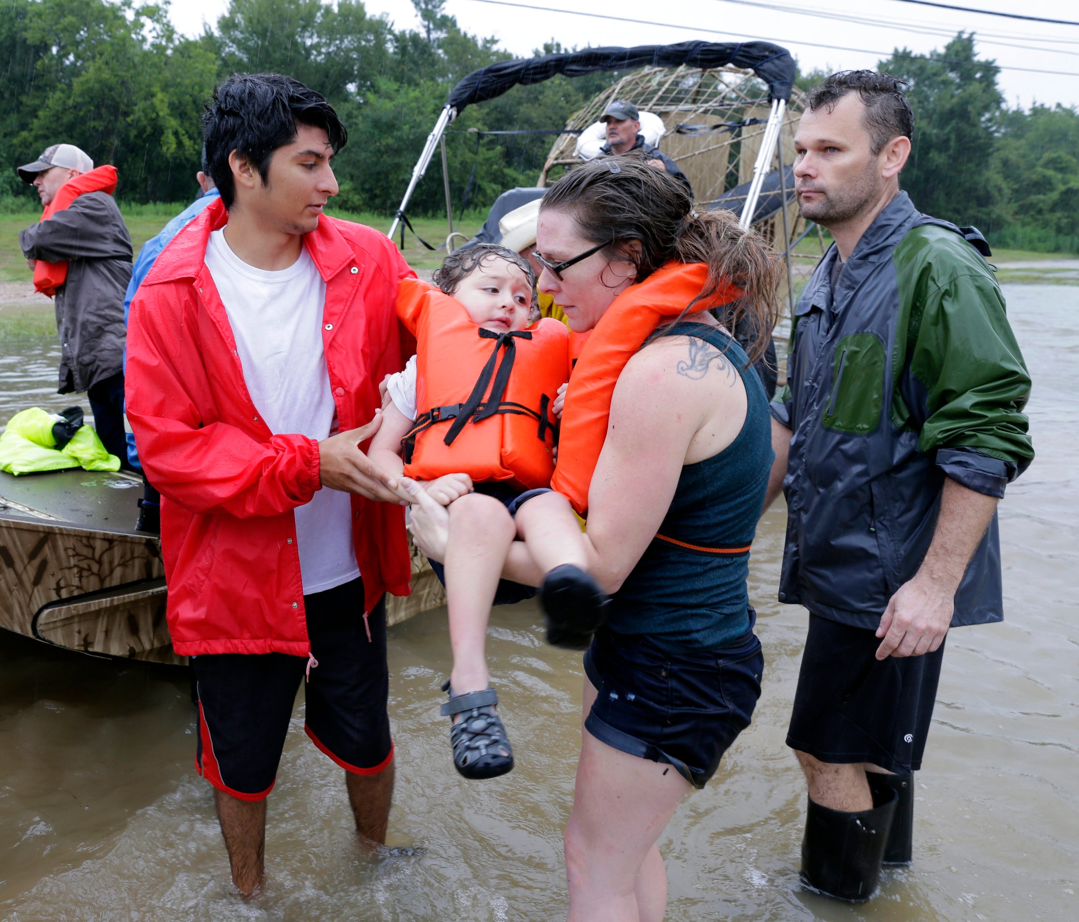  Mindy Walker and her three year old son Connor Martinez are helped out of a boat after being rescued from their home along Cypress Creek at Kuykendal 15 miles northwest of downtown Houston, Texas on Aug. 28, 2017. The areas in and around Houston and