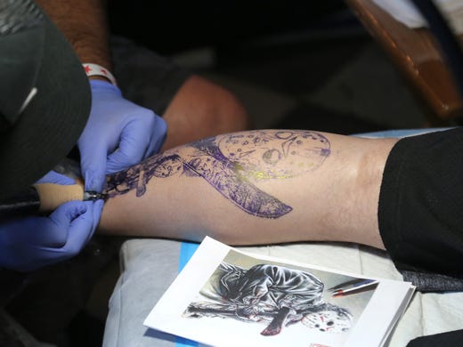 A tattoo artist inks up a patron during INKcarceration