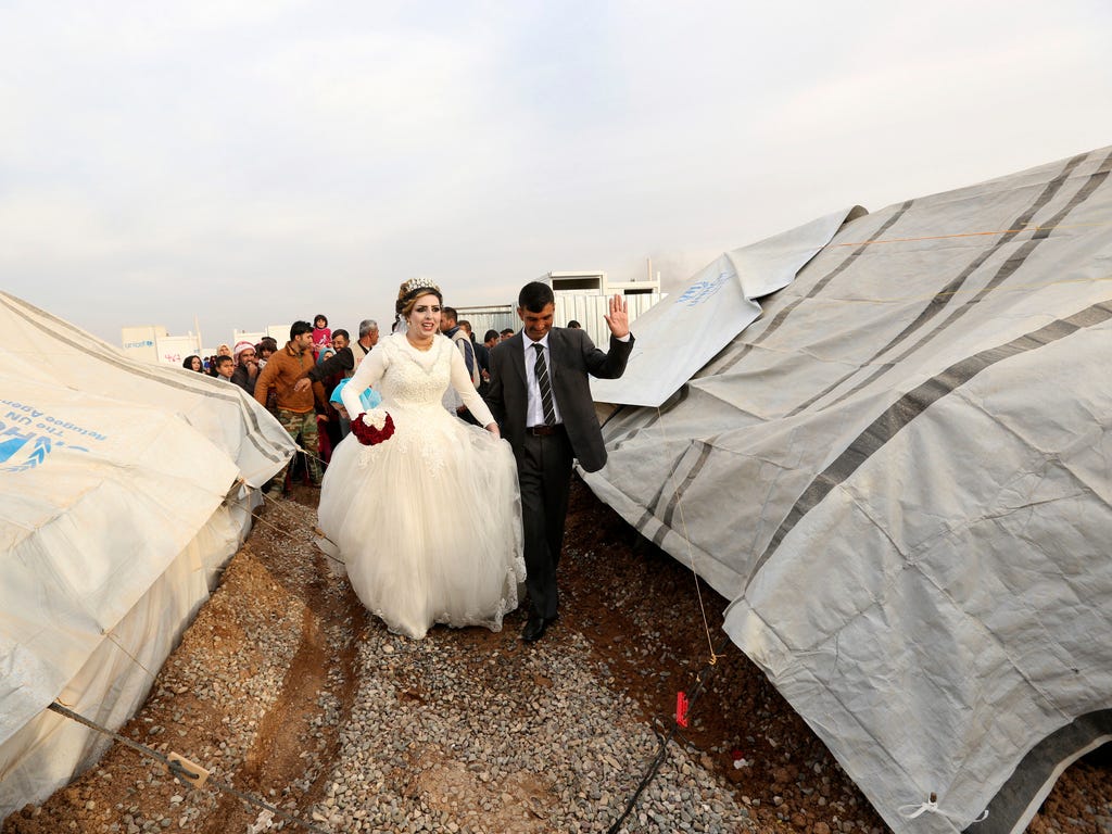 Jassim Mohammed walks with his bride, Amena Ali, during their wedding ceremony at a camp for internally displaced people, in Khazir, near Mosul, Iraq.