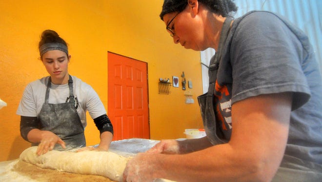 Owner Kris Kalmon, right, and her 14-year-old daughter Rainy, roll a dough in making cinnamon rolls Tuesday afternoon at One Love Bread in Withee.