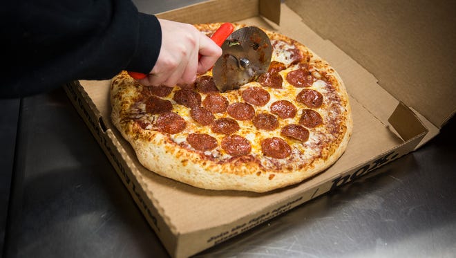 A pepperoni pizza is prepared for a customer at HotBox Pizza.