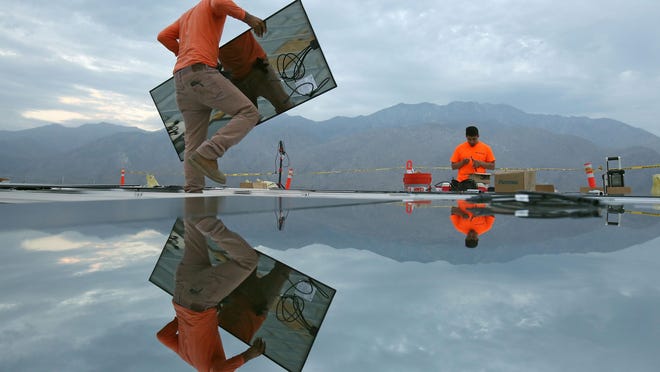 Charlie Quezada, left, and Anzony Gonzalez install solar panels at the Palm Springs Air Museum on Sept. 10, 2015.