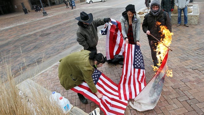 A group of protesters burn American flags on the pedestrian mall along Clinton Street on Thursday, Jan. 26, 2017. 