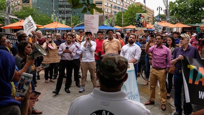 People listen to a speaker while protesting the Supreme Court ruling upholding the travel ban on travelers from several majority-Muslim nations by President Donald Trump's administration at Campus Martius in downtown Detroit on Tuesday, June 26, 2018.