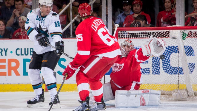 San Jose center Patrick Marleau tries to get the puck past Detroit goalie Petr Mrazek and Danny DeKeyser in the second period.  The Sharks won 6-4 Thursday.