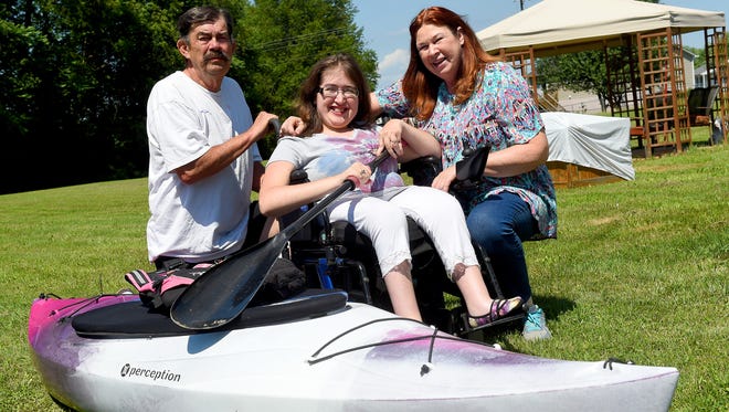 Savanna Stout sits between father John Stout and her mother, Anne Stout, next to her kayak outside their Stuarts Draft home on Tuesday, June 28, 2016. Although the family had problems over Memorial Day weekend while kayaking the South River, it will not keep them from enjoying the river. Savanna herself has not allowed spina bifida to keep her from learning skills necessary for kayaking and has been boating for eight years. 