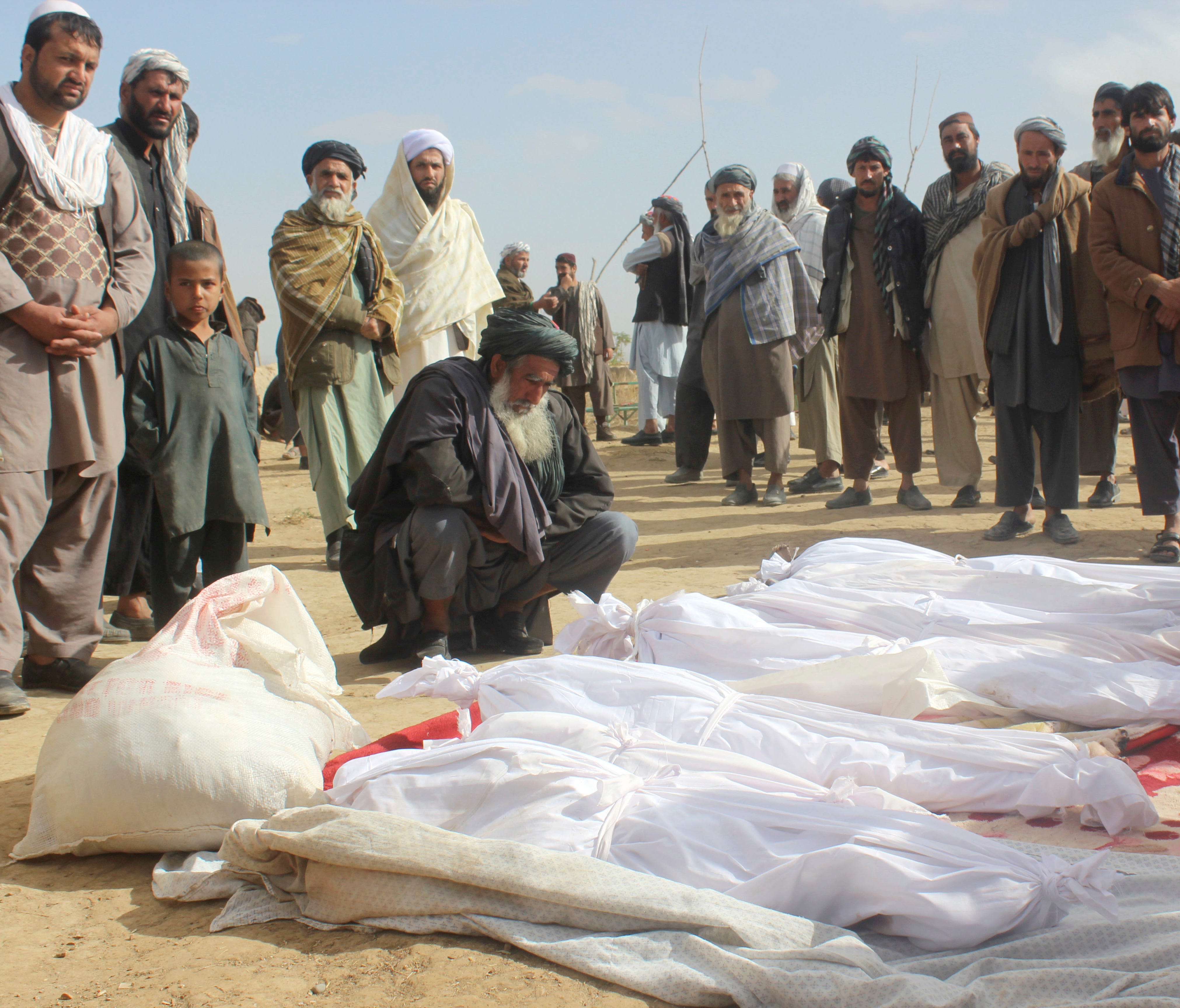 In this Nov. 4, 2016 file photo, Afghan villagers gather around several victims' bodies who were killed during clashes between Taliban and Afghan security forces in the Taliban-controlled, Buz-e Kandahari village in Kunduz province, Afghanistan.