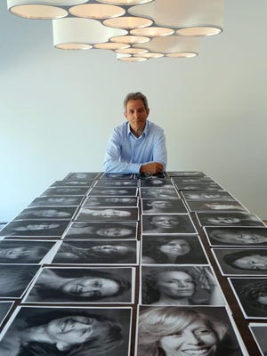 Photographer Peter Freed poses in his Rye studio with the black and white portraits he took of women aged 35 to 104 for a book he is working on.