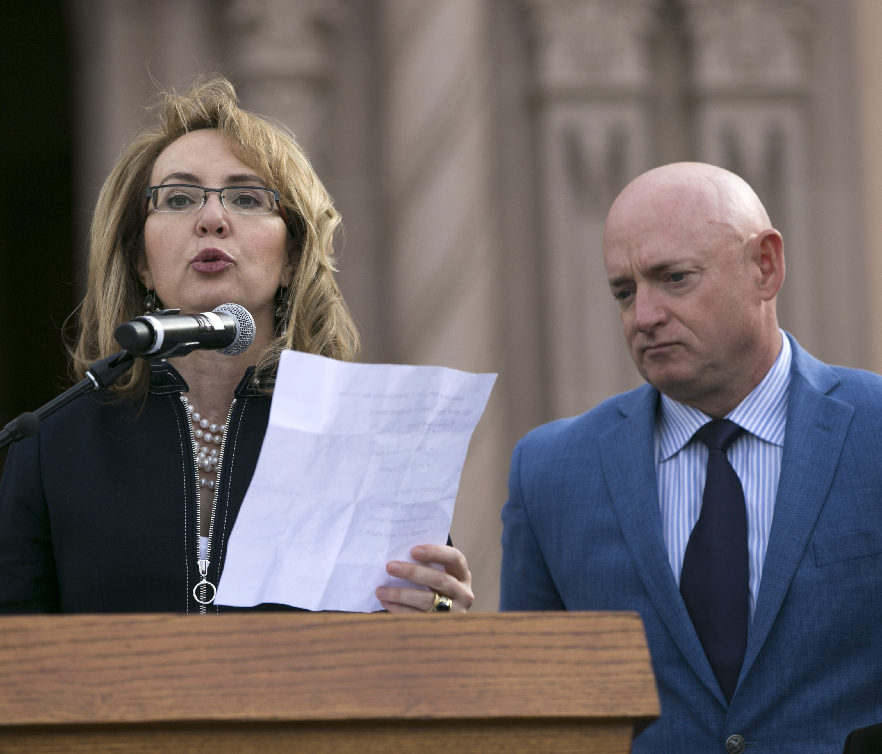 Former  U.S. Rep. Gabrielle Giffords speaks, as her husband, Mark Kelly looks on, during the memorial dedication for Tucson's January 8th Memorial at El Presidio Park in Tucson on Jan. 8, 2018. The dedication was held on the seven-year anniversary of