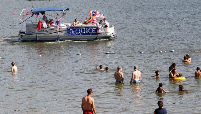 Passengers on a decorated boat entertain beach-goers on Lake MacBride during the Fourth of July boat parade in this file photo.