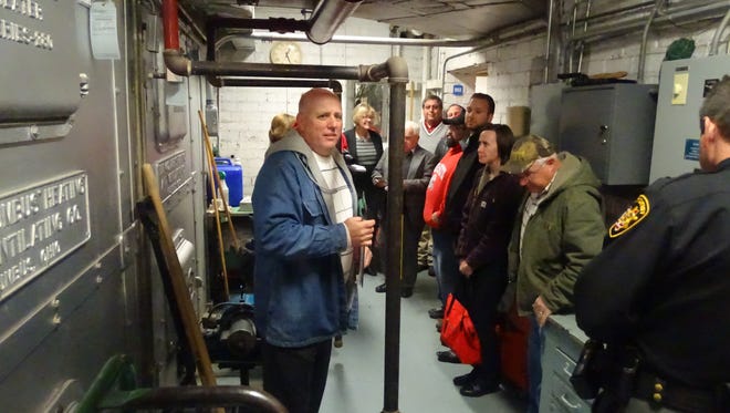 Conesville Elementary Principal Joel Moore, left, took residents on a tour of his school last November. Here, he showed visitors that the building's only wheelchair access leads through the school's furnace room and ends with steps.
