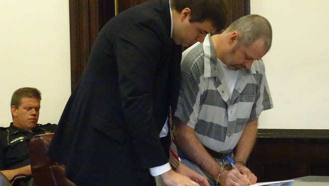 Dean Richard, of Fresno, signs papers waiving his right to stand trial and pleading guilty to kidnapping and other charges in Coshocton County Common Pleas Court. He remains in custody in the county jail while awaiting the results of a presentence investigation, requested by defense attorney Donald Regensburger, of Columbus, who assists him here.