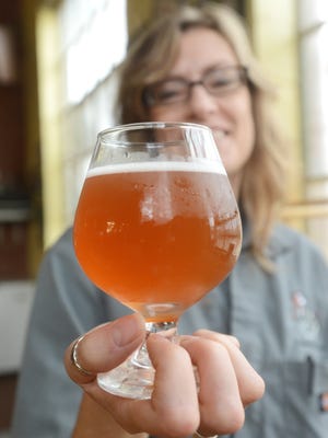 Lori Wince of Weasel Boy Brewing holds La Belette Rose, a Saison style beer she brewed for the brewery.