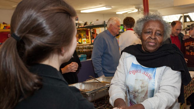 Annie Johnson thanks a volunteer at a community dinner held by Project Annie in 2013.