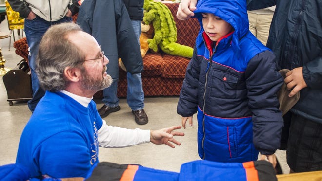 William Chafin, left, helps Tony Lavender, 7, try on a coat during the Knights of Columbus coat giveaway at St. Vincent DePaul Thrift Store Saturday, Dec. 12, 2015.