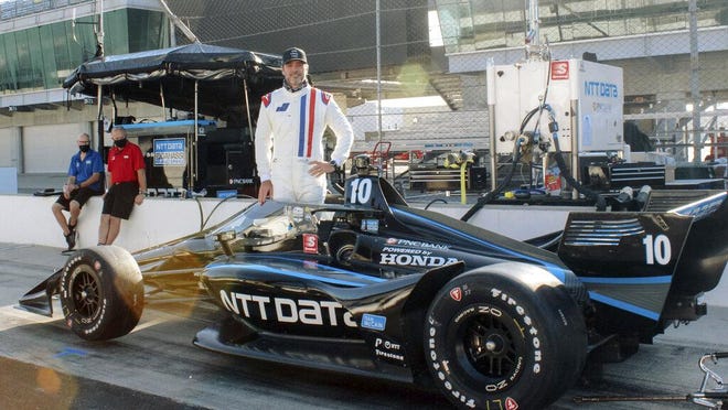 Seven-time NASCAR champion Jimmie Johnson poses with an IndyCar during testing with Chip Ganassi Racing on the road course at Indianapolis Motor Speedway.