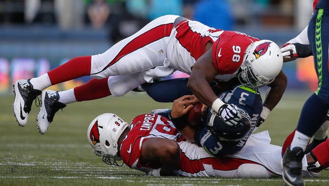 Seattle quarterback Russell Wilson is sacked by Arizona's Frostee Rucker (98) on Sunday, Nov. 23, 2014, in Seattle.