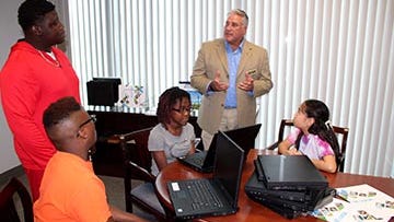 St. Lucie County Commissioner Chris Dzdovsky presents students with END IT six laptops donated from the county's Information Technology Department to help with the summer program.