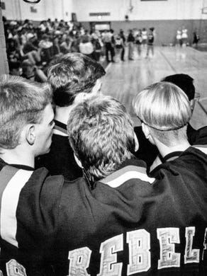 The 1991 West High School basketball team huddles at the door to the locker room as they wait for the girls team to finish play on the final game at the gym.