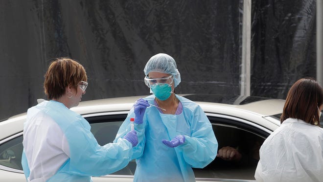 Health care personnel test a person in the passenger seat of a car for coronavirus at a Kaiser Permanente medical center parking lot in San Francisco.