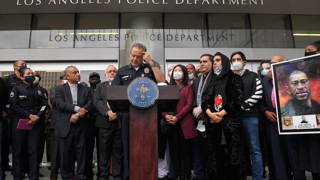 Los Angeles police chief Michel Moore, left, speaks as someone holds up a portrait of George Floyd during a vigil with members of professional associations and the interfaith community at Los Angeles Police Department headquarters, Friday, June 5, 2020, in Los Angeles.