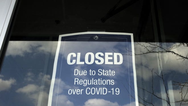 A closed sign is posted in the window of a store because of the coronavirus, in an outdoor mall, in Dedham.