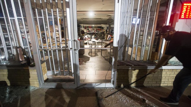 Workers sweep up broken glass outside Levels, a high-end clothing store on Auburn Street, and the Cricket phone store next door after the stores were looted after an hours-long peaceful protest turned violent on Sunday, May 31, 2020, in Rockford.
