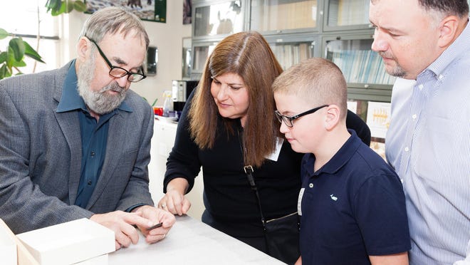 
Dennis Stanford (left) of the Smithsonian Institution examines the projectile point found by Noah Cordle, as the boy’s parents, Andrea and Brian Cordle, look on.
