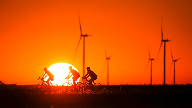 Riders pass in front of the rising sun outside Grand Junction on RAGBRAI 2018.