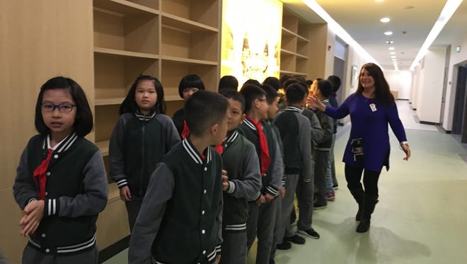 Port Clinton Middle School Principal Carrie Sanchez high fives students at a school in Hangzhou, China.
