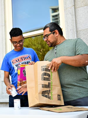 Nathan Newlin, left, of York City, and Sal Galdamez, a realtor and founder of York XL, fill paper bags with donated items following a press conference held to introduce 10,000 Acts of Kindness, a year-long collaborative effort to spread kindness and goodwill, outside of the York County Administrative Center in York City, Friday, June 29, 2018. Dawn J. Sagert photo