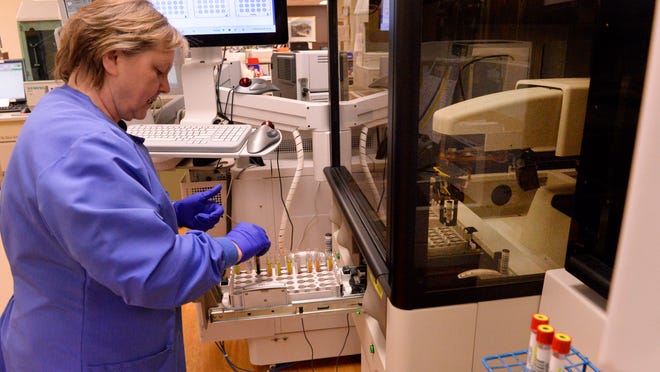 Teresa French, medical technologist working in the chemistry core lab, adds blood specimens to the new biochemistry clinical blood analyzer that performs up to 47 tests at a time at Holy Family Memorial in Manitowoc.