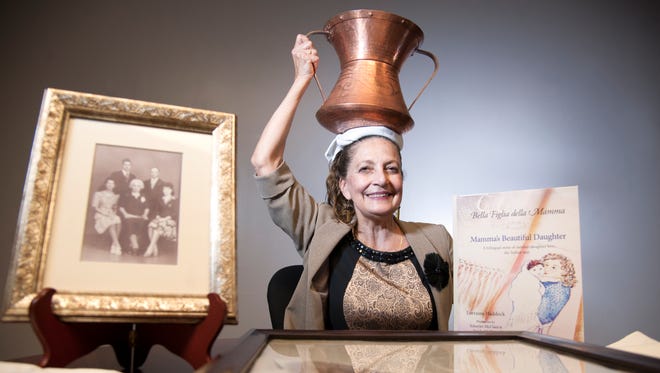 Lorraine Haddock of Gibbstown, author of the bilingual book titled "Mamma's Beautiful Daughter in English and Italian," demonstrates how her grandmother Giulia Gabrielli carried water from a well to her home in Italy.