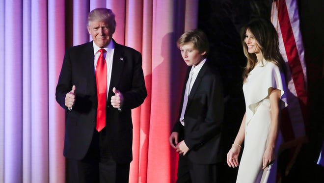 President elect Donald Trump motions to supporters as he and his son, Barron, center, and wife, Melania, walk on stage at an election night rally in the early morning hours of Nov. 9 in New York.