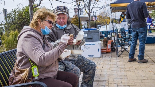 Lyuba Korsun, left, and her husband, Olex, confer over the taste of an Asian carp sandwich offered Saturday, Oct. 17, 2020 at the Levee District in East Peoria, one of two Tri-County locations, including Kelleher's in Peoria, promoting Asian carp as a culinary option. The Asian Carp Cookout was sponsored at multiple locations around the state by Illinois Department of Natural Resources Midwest Fish Co-op and Sorce Freshwater Company.