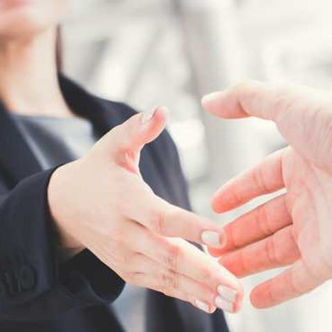 Woman in suit extending a handshake.