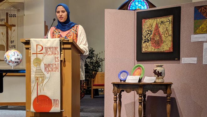Mayar Zamzam, 17, speaks at Christ Lutheran Church next to a display of artwork she created.