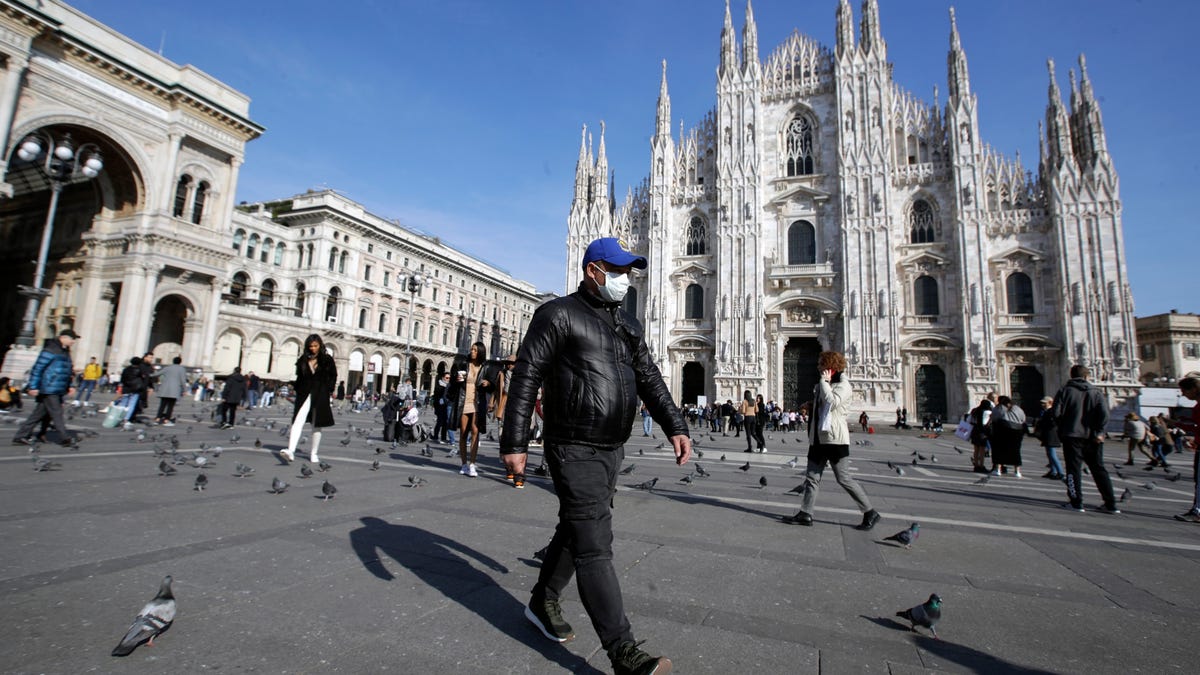 A man wearing a sanitary mask walks past the Duomo gothic cathedral in Milan, Italy, Monday, Feb. 24, 2020. Italy has been scrambling to check the spread of Europe's first major outbreak of the new viral disease amid rapidly rising numbers of infections and calling off the popular Venice Carnival, scrapping major league soccer matches in the stricken area and shuttering theaters, including Milan's legendary La Scala.   (AP Photo/Luca Bruno)