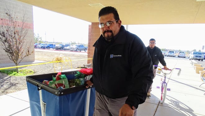 An Otero County Prison Facility corrections officer delivers Christmas gifts to students in need on Thursday as part of the prison's Angel Tree program.