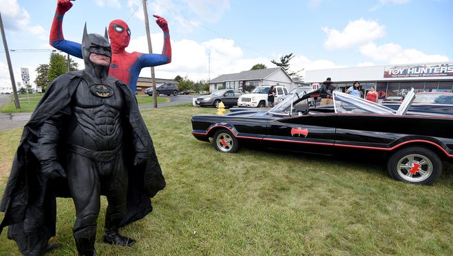 Batman and Spider-Man stand outside the new location of Toy Hunters with the Batmobile and engage drivers on Fourth Street on Friday afternoon.