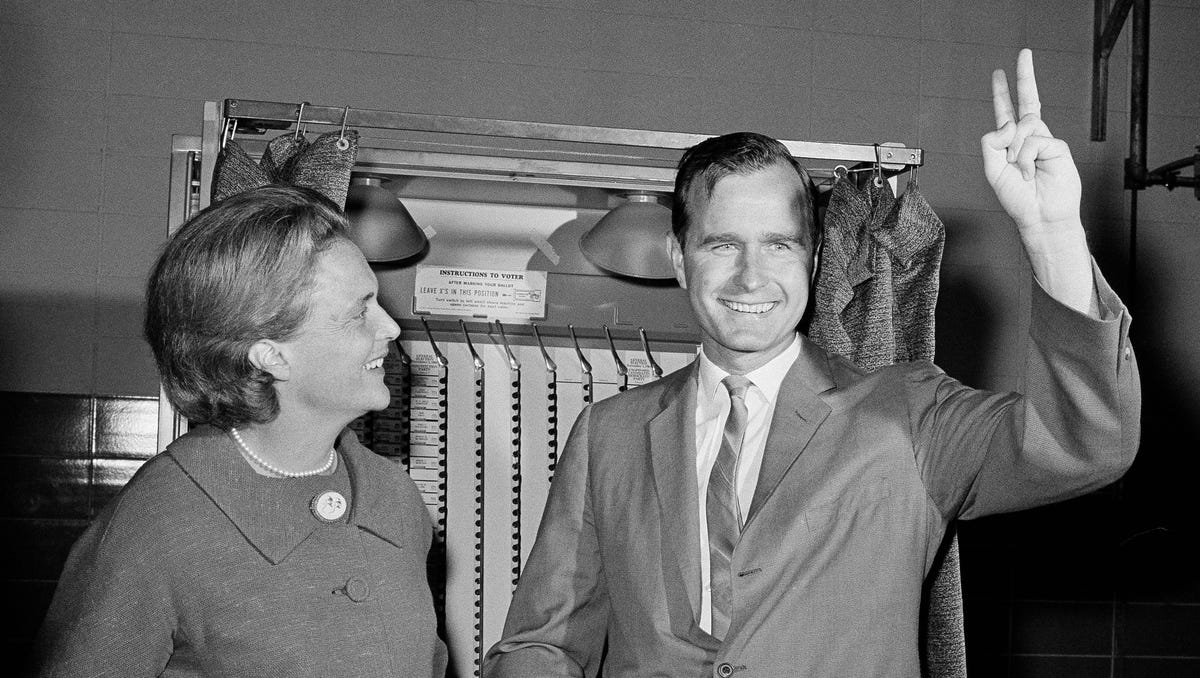 Republican Senatorial candidate George Bush shows a victory sign as he and his wife Barbara stand in front of a vote machine November 3, 1964 in Houston.