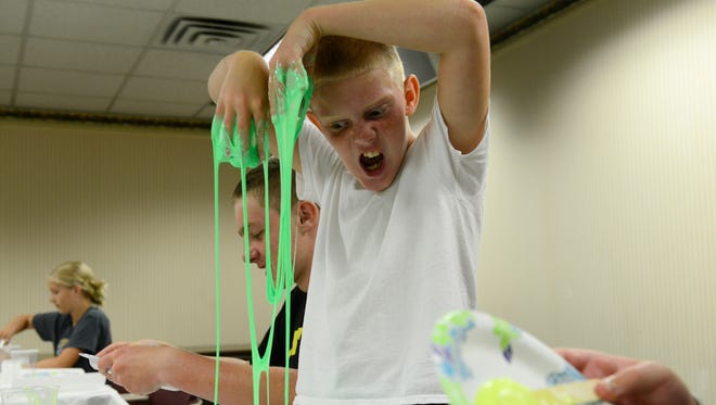 David Bryant, 11, right, and his brother, Anthony, 14, of Fremont mix up glow-in-the-dark slime to take home at the Birchard Public Library. The gooey fun was one of the Fremont library's summer kids programs held last week.